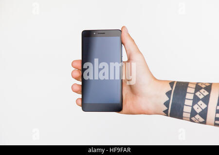 Male hand with a tattoo holding smartphone on white background. Branding Mock-Up. Stock Photo