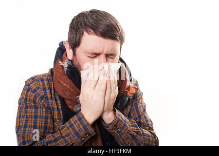 Closeup portrait of sick young man student or worker with allergy or germs cold, blowing his nose with kleenex, looking miserable unwell very sick, isolated on white background. Flu season, vaccine, Stock Photo