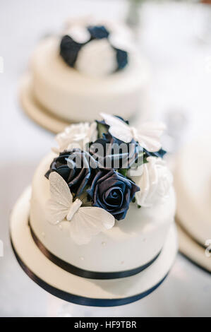Three white wedding cakes with blue floral decor.