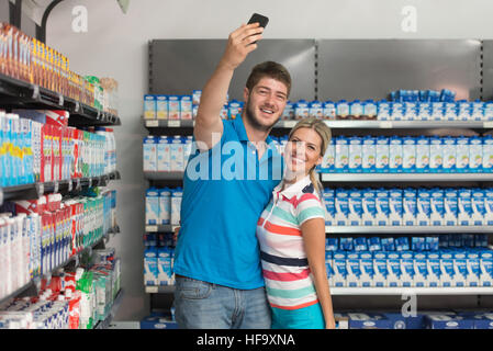 Beautiful Young Couple Taking A Selfie In Supermarket Shopping For Milk And Cheese In Produce Department Of A Grocery Store - Shallow Deep Of Field Stock Photo