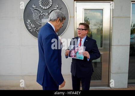 U.S. Embassy Deputy Chief of Mission Matt Roth shows U.S. Secretary of State John Kerry a photo of his wife and children back home in the United States before the Secretary greets staff members and their families from U.S. Embassy Kigali during a visit to the Rwandan capital on October 14, 2016, to attend a conference focused on amending the Montreal ozone layer protection protocol. Stock Photo