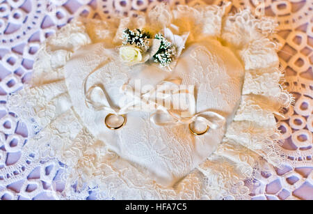 Double gold rings tied on a white pillow white heart-shaped Stock Photo