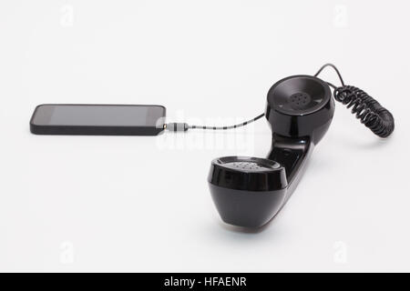 Old phone reciever and cord connection with new phone. Funny hotline concept. Stock Photo
