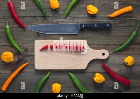 chopped cayenne chilli pepper on cutting board with peppers around Stock Photo