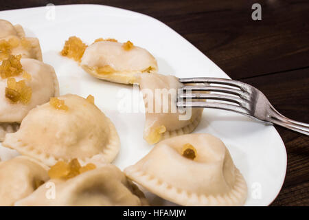 Traditional polish dumplings, 'pierogi ruskie' on white plate on wooden table. Stock Photo