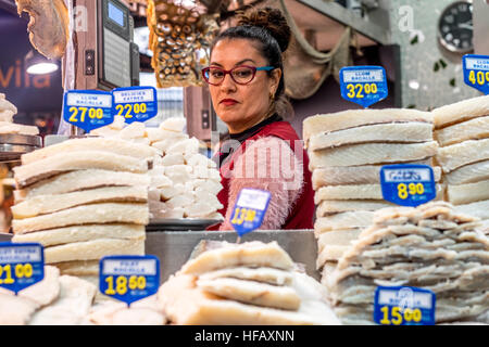 A woman looks slyly over her fish stacks in Barcelona. Stock Photo