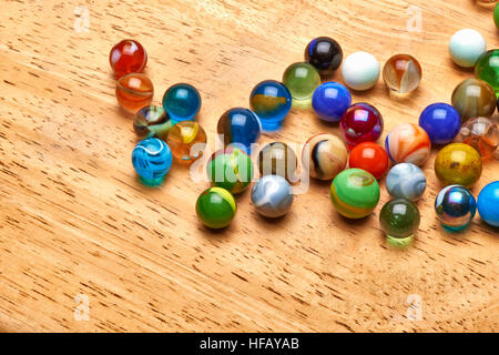 Lot of Multi colored Marbles on wooden board Stock Photo