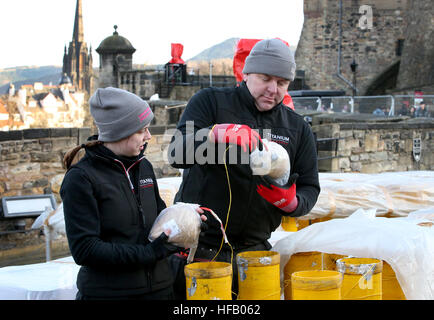 Pyro-technicians Shaun Gibson and Lynn Wiseman from Titanium Fireworks set up some of the 2.6 tonnes of fireworks along the ramparts of Edinburgh Castle ahead of the Hogmanay fireworks display for the New Year. Stock Photo