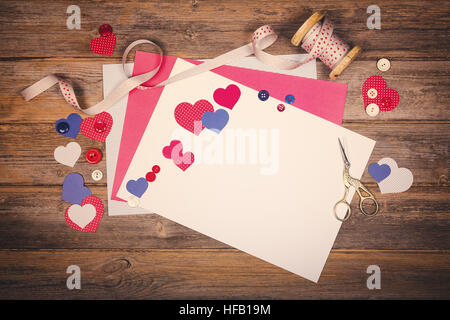 A vintage scrapbooking themed background with cutout hearts, craft paper, ribbon and buttons. Space for your text. Filtered to look like an old photo Stock Photo