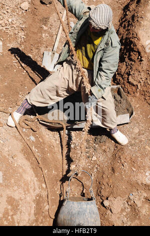 Afghan workers and coalition forces collaborate to remove debris and repair a collapsed karez on Shindand Air Base, Herat province, restoring water supply for over a thousand families after flooding, while providing local employment opportunities. Stock Photo