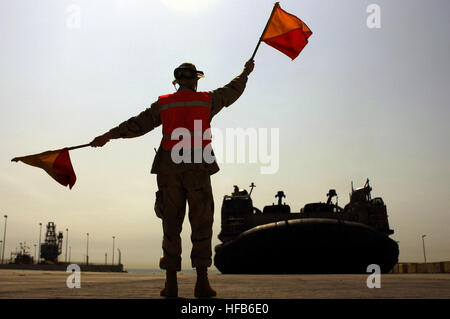 050601-N-4309A-171  Navy Seaman Charles Shafer, from Beach Master Unit 2, uses flags to signal to the craftmaster of a Navy Landing Craft Air Cushion, or LCAC, at a Kuwaiti Naval Base staging area on June 1, 2005.  The LCAC, assigned to Assault Craft Unit 4 based in Little Creek, Va., is deployed in the Northern Persian Gulf with the USS Kearsarge (LHD 3) and USS Ashland (LSD 48) in support of transport operations with the 26th Marine Expeditionary Unit.  DoD photo by Petty Officer 1st Class Aaron Ansarov, U.S. Navy.  (Released) Defense.gov News Photo 050601-N-4309A-171 Stock Photo