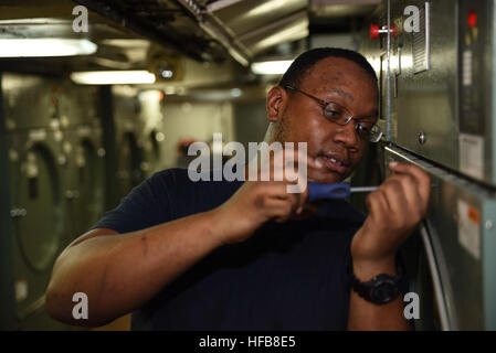 161012-N-IE397-116    ARABIAN GULF (Oct. 12, 2016) Seaman Osei Brown, from Riverhead, New York, screws the panel of a washing machine back into place in the division laundry compartment of the aircraft carrier USS Dwight D. Eisenhower (CVN 69) (Ike). Brown serves aboard Ike as an electrician's mate and helps inspect, repair and maintain Ike's electrical systems. Ike and its Carrier Strike Group are deployed in support of Operation Inherent Resolve, maritime security operations and theater security cooperation efforts in the U.S. 5th Fleet area of operations. (U.S. Navy photo by Seaman Christop Stock Photo