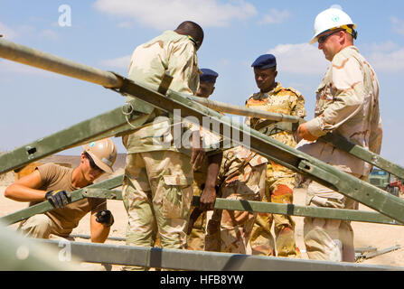 Chief Travis Canaday, construction electrician, in the white hardhat, and Builder 3rd Class Robert Cotter, in the brown hardhat, both Sailors from Naval Mobile Construction Battalion 3 from Port Hueneme, Calif. and currently assigned to Combined Joint Task Force - Horn of Africa help teach soldiers of the Djiboutian army how to assemble a 64-foot Temper Tent, Nov. 2, on a range of Doudoub Bolole. This tent, and five others, were donated by the U.S. Navy to the Djiboutian army for an upcoming Djiboutian military field exercise being held late 2009. The Djiboutian military will utilize the tents Stock Photo