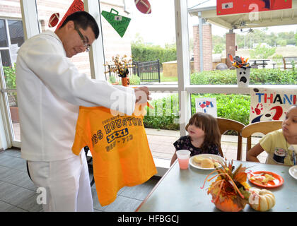 HOUSTON (Oct. 26, 2012) Sonar Technicican (Submarine) 3rd Class Rodolfo Sosa, assigned to the Los Angeles-class attack submarine USS Houston (SSN 713), gives a command t-shirt to a child at Houston's Ronald McDonald House during Houston Navy Week. Houston Navy Week is one of 15 selected cities where residents will get an opportunity to meet Sailors and learn about the Navy's capabilities and relevance to national security. The U.S. Navy has a 237-year heritage of defending freedom and projecting and protecting U.S. interests around the globe. Join the conversation on social media using #warfig Stock Photo