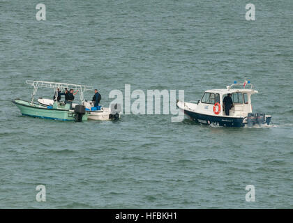 MINA SALMAN PIER, Bahrain (Oct. 29, 2012) A Royal Bahrain Coast Guard vessel escorts two skiffs that belong to Bahraini fisherman who were rescued by the Afloat Forward Staging Base (Interim) USS Ponce (AFSB(I) 15) during heavy weather. The seven fishermen were assisted aboard by Ponce's crew, treated by the ship's medical staff and returned to shore in Bahrain. Ponce, formerly designated as an amphibious transport dock (LPD) ship, was converted and reclassified to fulfill a longstanding U.S. Central Command request for an AFSB to be located in its area of responsibility. The U.S. Navy is cons Stock Photo