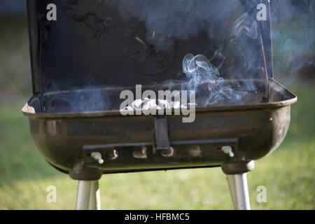 Charcoal smoking in open grill Stock Photo