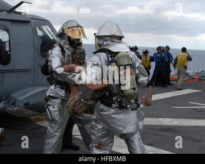 Crash and salvage personnel rescue a simulated casualty during a flight deck fire drill aboard amphibious assault ship USS Tarawa. Tarawa along with embarked 11th Marine Expeditionary Unit is on a scheduled deployment to the Western Pacific in support of maritime security operations and the global war on terrorism. Flight deck firefighters attack a simulated fire on USS Tarawa 64616 Stock Photo