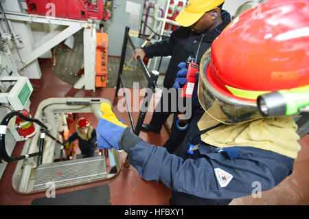 150309-N-UG232-135 WATERS TO THE EAST OF THE KOREAN PENINSULA (March 10, 2015) Damage Controlman 3rd Class Rhashida Kelly signals to Electronics Technician 2nd Class Edward Von Schondorf as they check the limits of a simulated fire as part of damage control training aboard USS Lassen (DDG 82) during exercise Foal Eagle 2015. Foal Eagle is a series of annual training events that are defense-oriented and designed to increase readiness and maintain stability on the Korean Peninsula while strengthening the ROK-U.S. alliance and promoting regional peace and stability of the Indo-Asian-Pacific regio Stock Photo