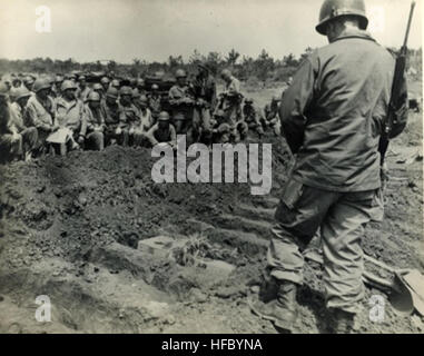 **ADVANCE FOR MONDAY, FEB. 4** This photo provided by Richard Strasser shows the scene on April 20, 1945, two days after his death on Ie Shima, where correspondent Ernie Pyle was buried alongside several soldiers killed in combat on the tiny island off Okinawa   the kind of men Pyle had written about during four years of WWII battlefield reporting. The photo shows a memorial ceremony led by Maj. Gen. Andrew D. Bruce (back to camera), commander of the Army's 77th Infantry Division, which captured the island the next day. Ernie Pyle's wooden coffin, with his picture and a sprig of foliage, is vi Stock Photo