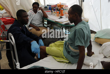 Petty Officer 2nd Class James Abbington, hospital corpsman, a physical therapist from Port Arthur, Texas, embarked aboard the Military Sealift Command hospital ship USNS Comfort, talks to a Haitian earthquake victim about his recovery at St. Damien Hospital in Port-au-Prince. Abbington and other Comfort Sailors, visited St. Damien to assess medical needs of the hospital and to assist recovering patients with rehabilition from injuries suffered in a 7.0 magnitude earthquake Jan. 12, 2010. Comfort is participating in Operation Unified Response by providing medical support capabilities in Haiti.  Stock Photo