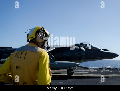 PACIFIC OCEAN (Feb. 23, 2015) -- Chief Aviation Boatswain’s Mate (Handling) Nnamdi Emenogu looks on as an AV-8B Harrier, assigned to Marine Attack Squadron (VMA) 311, approaches the flight deck of amphibious assault ship USS America (LHA 6). America is currently conducting training maritime operations of the coast of California. The ship is the first of its class and is optimized for Marine Corps aviation. (U.S. Navy photo by Aviation Boatswain’s Mate (Handling) Airman John Kelvin Chavez/Released). Harrier operations 150223-N-ZZ999-224 Stock Photo