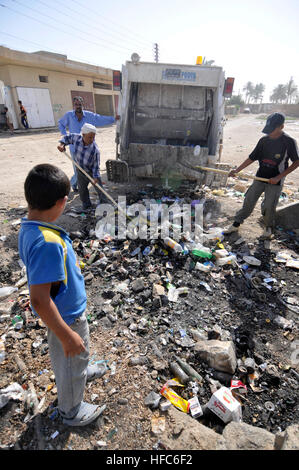 A small Iraqi boy looks on as local residents clear away a garbage pile.  Meanwhile, Iraqi soldiers from the 1st Battalion, 23rd Brigade, 17th Iraqi Army Division, conduct joint patrols with U.S. Soldiers from 2nd Platoon, Bravo Troop, 1st Battalion, 150th Armored Reconnaissance Squadron, 30th Heavy Brigade Combat Team, 1st Cavalry Division, from Bluefield, W.Va., in the village of Yusifiyah, Iraq, Aug. 16. Joint patrol 196942 Stock Photo