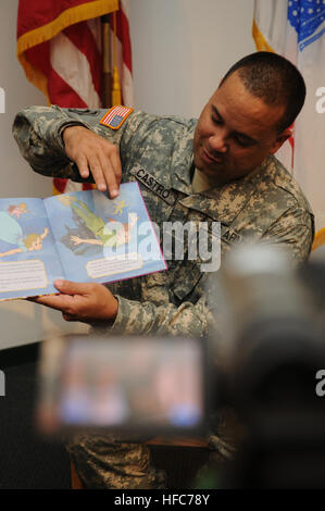 Army Sgt. Nazario Castro, attached to Joint Detention Group Joint Task Force Guantanamo, reads a Peter Pan book to his two sons while being recorded as part of the United Through Reading program, at the Trooper Chapel on Guantanamo Bay, April 4. The program sponsors books to service members and, also provides the video to be sent to the member’s family while they are deployed. JTF GTMO troops parent from afar 110404-N-AT101-020 Stock Photo