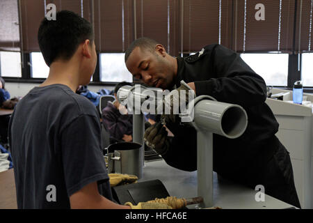 Machinist's Mate 1st Class Marteaus Dykes shows a student from Mira Mesa High School Air Force Junior ROTC how to patch pipe during a tour of the Submarine Learning Center Detachment in San Diego. The students experienced the ship's control station trainer, damage control trainers and the VESUB 2000 virtual submarine trainer during the tour. Machinist's Mate 1st Class Marteaus Dykes shows a student from Mira Mesa High School Air Force Junior Reserve Officer Training Corps (JROTC) how to patch pipe Stock Photo