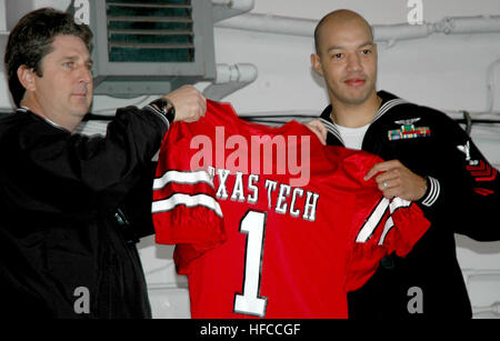041227-N-5517C-077  San Diego, Calif. (Dec. 27, 2004) - Texas Tech Head Coach Mike Leach presents Air Traffic Controller 1st Class Mitchel Deshotel a team jersey and making him an honorary team captain. Deshotel will join the team during the game at Qualcomm Stadium in San Diego, Calif. The amphibious assault ship USS Tarawa (LHA 1) hosted the 27th Pacific Life Holiday Bowl luncheon for players from the “Golden Bears” of University of California and the “Red Raiders” of Texas Tech University. The teams will play in the bowl game on December 30, 2004 at Qualcomm Stadium in San Diego, California Stock Photo