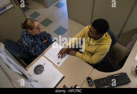 140313-N-DJ750-014 SAN DIEGO (March 13, 2014) Julian Duhe, an education service specialist, reads tuition assistance options to a Sailor at the Navy College Office at Naval Base San Diego. Navy College offices are located at 36 installations around the world and advise service members how to complete their high school diploma, work on technical or occupational certificates or earn a college degree. (U.S. Navy photo by Mass Communication Specialist 3rd Class Bryan Jackson/Released) Navy College Office 140313-N-DJ750-014 Stock Photo