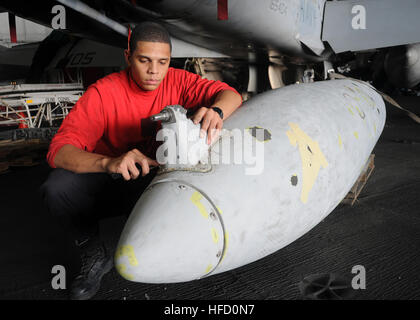 A Seaman Apprentice performs corrosion repair on a drop tank in the hangar bay of the Nimitz-class aircraft carrier USS Dwight D. Eisenhower. Eisenhower is deployed as part of a rotation of forward-deployed forces supporting maritime security operations in the U.S. 5th Fleet area of responsibility. Stock Photo