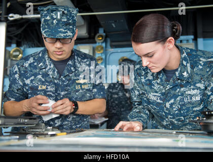 OKINAWA, Japan (Jan. 22, 2013) Quartermaster 2nd Class Brittnee McKinney assists Lt. j.g. McKinley Kim, the ship's navigator, with course navigation aboard the Whidbey Island-class amphibious dock landing ship USS Tortuga (LSD 46). Tortuga is part of the Bonhomme Richard Amphibious Ready Group and is operating in the U.S. 7th Fleet area of responsibility. (U.S. Navy photo by Mass Communication Specialist 3rd Class Gregory A. Harden II/Released) 130122-N-HI414-080  Join the conversation http://www.facebook.com/USNavy http://www.twitter.com/USNavy http://navylive.dodlive.mil Sailors plot the shi Stock Photo