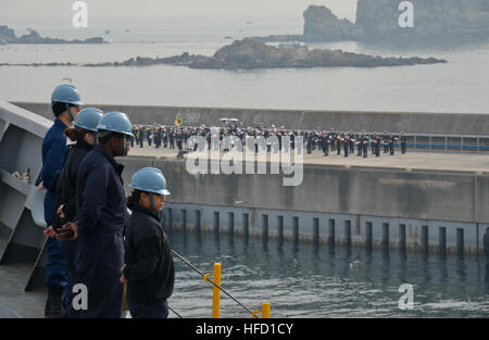 BUSAN, South Korea (March 17 2015)  Sailors assigned to the submarine tender USS Frank Cable man the rails as they depart the Republic of Korea (ROK). Sailors from the ROK Navy bid them farewell on the pier as the ship began to depart.  Frank Cable, forward deployed to the island of Guam, conducts maintenance and support of submarines and surface vessels deployed in the U.S. 7th Fleet area of responsibility and is currently on a scheduled underway period. (U.S. Navy photo by Mass Communication Specialist 3rd Class Jason Amadi/Released) Sailors visit Jinhae Naval Base 150317-N-XX999-001 Stock Photo