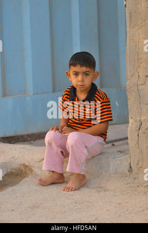 A small Iraqi boy looks on as U.S. Soldiers of the 4th Cavalry Regiment, 5th Squadron, 2nd Heavy Brigade Combat Team, 1st Infantry Division, assist the Iraqi Sayfafia National Police conduct door-to-door search operations in Ghazaliyah, Iraq, July 15. Soldiers support Iraqi national police 188145 Stock Photo