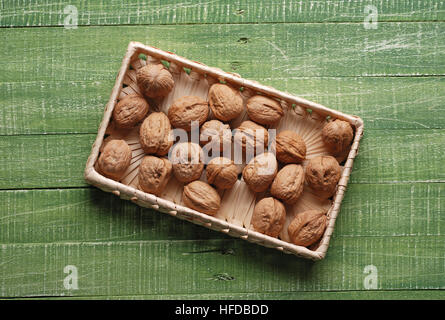 Walnuts in the basket on the green table Stock Photo