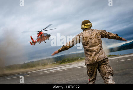 U.S. Marine Corps Lance Cpl. Corey Butlerstallworth, attached Combat Logistics Battalion 23, signals to the pilot of a U.S. Coast Guard MH-65 Dolphin helicopter to land during a medical drill for Joint Logistics Over-The-Shore 2016 (JLOTS ’16) on Naval Magazine Indian Island, Wash., June 9, 2016 . JLOTS ’16 is a joint-service, scenario-based exercise designed to simulate disaster and humanitarian assistance in the Cascadia Subduction Zone. (U.S. Navy photo by Mass Communication Specialist 2nd Class Eric Chan/Released) U.S. Forces Take Part in JLOTS '16 160609-N-KK081-097 Stock Photo