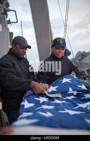 U.S. Navy Fire Controlman 2nd Class Cedric Bussey, left, and Quartermaster Seaman Recruit Tayler Simpkins fold a U.S. flag aboard the guided missile destroyer USS Stout (DDG 55) as the ship prepares to pull into port in Haifa, Israel, Jan. 19, 2014, for a scheduled port visit. The ship was on a scheduled deployment supporting maritime security operations and theater security cooperation efforts in the U.S. 6th Fleet area of responsibility. (U.S. Navy photo by Mass Communication Specialist 2nd Class Amanda R. Gray/Released) U.S. Navy Fire Controlman 2nd Class Cedric Bussey, left, and Quartermas Stock Photo