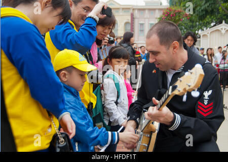 Musician 1st Class Brian Nefferdorf of the U.S. 7th Fleet Band's Pacific Ambassadors teaches a little boy how to play the banjo while the band performs in front of an audience of 800 people at Hong Kong Disneyland. Sailors from the U.S. 7th Fleet flagship USS Blue Ridge (LCC 19) are in Hong Kong for a port visit. (U.S. Navy photo by: Mass Communication Specialist 3rd Class James Norman) US 7th Fleet Band in Hong Kong 120319-N-SD300-066 Stock Photo