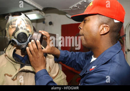 020423-N-0685W-004 At sea aboard USS Kitty Hawk (CV 63) Apr. 23, 2002 -- Damage Control Training Team member, Storekeeper 1st Class Kerry Bean (right) from Bruce, MS, and Aviation Storekeeper Airman Ying Guan, from Los Angeles, CA, discuss and demonstrate the proper use of a C2 canister, and its proper gas mask assembly during a general quarters training exercise.  Kitty Hawk is providing a forward presence in the Asia-Pacific region, conducting training and exercises with its regional allies.  Kitty Hawk is the NavyÕs only permanently forward-deployed aircraft carrier operating out of Yokosuk Stock Photo