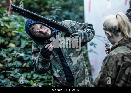 Groups of people dressed up in combat camouflage  uniforms and carrying paint-ball guns hunting zombies in the woods in a 'The Walking Dead Experience' Live Action Role Play  (LARP) activity event on a November afternoon in woodlands near Aberystwyth Wales UK Stock Photo