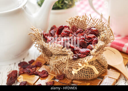 Dried cranberries in burlap bag on white rustic table Stock Photo
