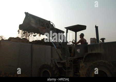 041027-N-5386H-021  Al Anbar Province, Iraq (Oct. 27, 2004) - Navy Reserve Seabee Equipment Operator 2nd Class Christopher Borchert, assigned to Naval Mobile Construction Battalion Two Three (NMCB-23), loads dirt into sandbag barriers surrounding a building at a Coalition Forces camp in Al Anbar Province, western Iraq. Known by the brand name Hessco, the barriers are a common site at military camps throughout Iraq, providing concealment and force protection. U.S. Navy photo by PhotographerÕs Mate 2nd Class Michael D. Heckman (RELEASED) US Navy 041027-N-5386H-021 Navy Reserve Seabee Equipment O Stock Photo