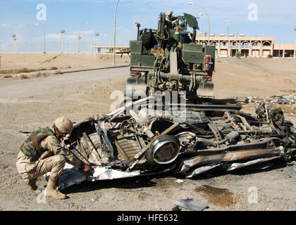 041118-N-4388F-006 Fallujah, Iraq (Nov. 18, 2004) - Construction Mechanic 2nd Class Thomas Tupling, assigned to Naval Mobile Construction Battalion Four (NMCB-4), attaches a tow cable to a demolished car prior to removing it from a street in Fallujah, Iraq. NMCB-4 is homeported in Port Hueneme, California and is currently deployed in support of Operation Al Fajr (New Dawn). Operation Al Fajr is an offensive operation to eradicate enemy forces within the city of Fallujah in support of continuing security and stabilization operations in the Al Anbar province of Iraq. U.S. Navy photo by Photograp Stock Photo