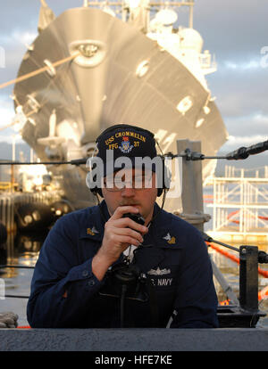 050104-N-5039H-002 Pearl Harbor, Hawaii (Jan. 4, 2005) - Electronics Technician 1st Class Michael J. Hanna, assigned to the CS-4 Division aboard the guided missile frigate USS Crommelin (FFG 37), tests a sound power phone line before the ship leaves Naval Station Pearl Harbor, Hawaii. The guided missile cruiser USS Port Royal (CG 73), background, is currently in dry dock on board Naval Station Pearl Harbor. While underway, Crommelin will perform combat systems drills, small arms training, update their damage control qualifications and basic watch standing requirements. U.S. Navy photo by Photo Stock Photo