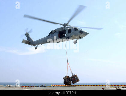 050106-N-9214D-060 Indian Ocean (Jan. 6, 2005) Ð An MH-60S Knighthawk helicopter assigned to the ÒGunbearersÓ of Helicopter Combat Support Squadron Eleven (HC-11), lifts off with a cargo net of relief supplies, from the flight deck of the amphibious assault ship USS Bonhomme Richard (LHD 6). Helicopters from Bonhomme Richard and Sailors and Marines assigned to Expeditionary Strike Group Five (ESG-5) are supporting Operation Unified Assistance, the humanitarian operation effort in the wake of the Tsunami that struck South East Asia. The Bonhomme Richard Expeditionary Strike Group is currently o Stock Photo