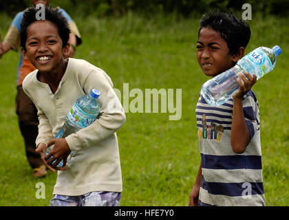 050109-N-4166B-141 Tjalang, Sumatra, Indonesia (Jan. 9, 2005) - Indonesian children smile as they receive much-needed bottles of water flown-in by a Navy Seahawk helicopter. Helicopters assigned to Carrier Air Wing Two (CVW-2) and Sailors from Abraham Lincoln are supporting Operation Unified Assistance, the humanitarian operation effort in the wake of the Tsunami that struck South East Asia. The Abraham Lincoln Carrier Strike Group is currently operating in the Indian Ocean off the waters of Indonesia and Thailand.  U.S. Navy photo by Photographer’s Mate Airman Jordon R. Beesley (RELEASED) US  Stock Photo