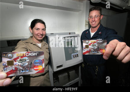 050215-N-3228G-002 Pearl Harbor, Hawaii (Feb. 15, 2005) - Disbursing Officer, Lt.j.g. Elizabeth Williams, left, and Disbursing Clerk 1st Class Michael Brett, display their Navy Cash Cards in front of a K80 terminal aboard the guided missile cruiser USS Lake Erie (CG 70). The system, which began March 23, 2004, eliminates cash and coins from the entire ship and instead requires Sailors to add money from their personal bank accounts to one of two systems held on the cash card. U.S. Navy photo by Photographer's Mate 1st Class William R. Goodwin (RELEASED) US Navy 050215-N-3228G-002 Disbursing Off Stock Photo