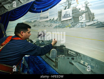 040527-N-7871M-071 Arabian Gulf (May 27, 2004) - Electronics Technician 3rd Class Juan Solorzano of El Paso, Texas, works from photographs to paint a mural depicting various scenes of USS George Washington (CVN 73) on an elevator door. The mural will cover more than 2,500 square feet and will take more than six weeks to complete. The Norfolk, Va. based nuclear powered aircraft carrier and Carrier Air Wing Seven (CVW-7) are on a scheduled deployment in support of Operation Iraqi Freedom (OIF). U.S. Navy photo by Photographer's Mate Airman Andrew Morrow (RELEASED) US Navy 040527-N-7871M-071 Elec Stock Photo