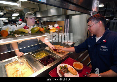 040419-N-9849W-062 At sea Aboard USS Coronado (AGF 11) Apr. 19, 2004 - Kasey Gould, a civilian mariner assigned to the Military Sealift Command (MSC), hands a portion of vegetables to Information Systems Technician 1st Class Jorge Handal aboard USS Coronado (AGF 11). Coronado is serving as the temporary command ship for U.S. Seventh Fleet while USS Blue Ridge (LCC 19) is in a scheduled dry dock maintenance period. Handal, a Sailor supporting the Seventh Fleet staff, is assigned to Blue Ridge. Besides serving as a temporary command ship, Coronado is also experimenting with a unique manning conc Stock Photo