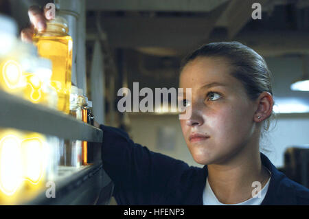 030910-N-1671M-005 Indian Ocean (Sept. 10, 2003) -- Searching for water or other impurities that can cause contamination, Gas Turbine System Technician Fireman Molly Jarvis from Falls City, Ore., examines a lube oil sample from the gas turbine propulsion system in the main machinery room aboard USS Bridge (AOE 10).  This is Bridge's last deployment as a United States Ship.  Several months after arrival in its homeport of Bremerton, Wash., Bridge will decommission and join the Military Sealift Command, becoming USNS Bridge (T-AOE 10).  Bridge is deployed with the Nimitz Carrier Strike Force in  Stock Photo